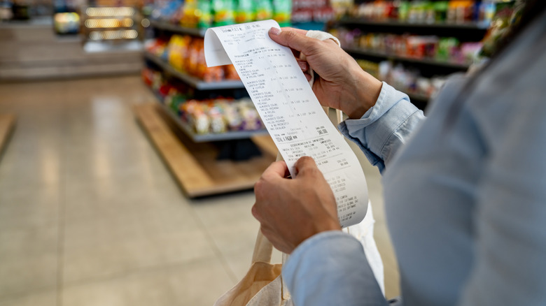 Person in a grocery store looking at their reciept