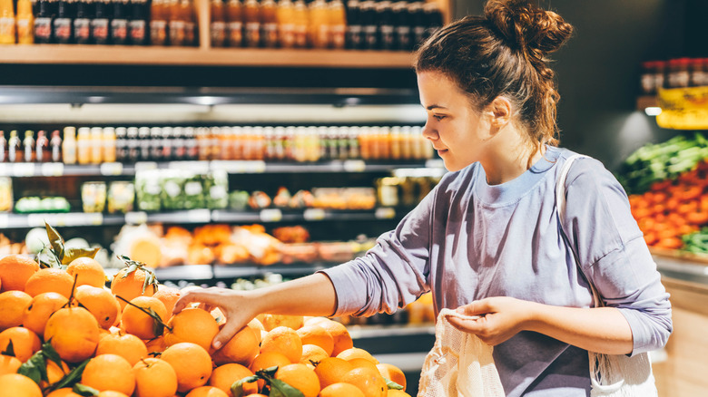 Woman in grocery store choosing an orange