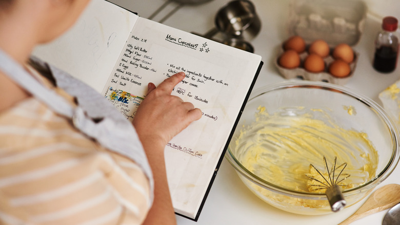 Person reading a recipe carefully while baking
