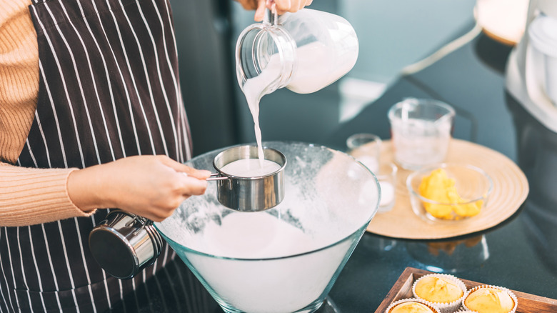 Person pouring milk in measuring cup