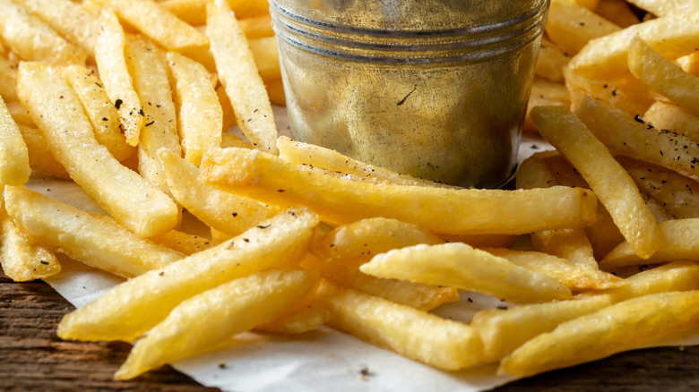 French fries in tin bucket with whole potatoes in the background