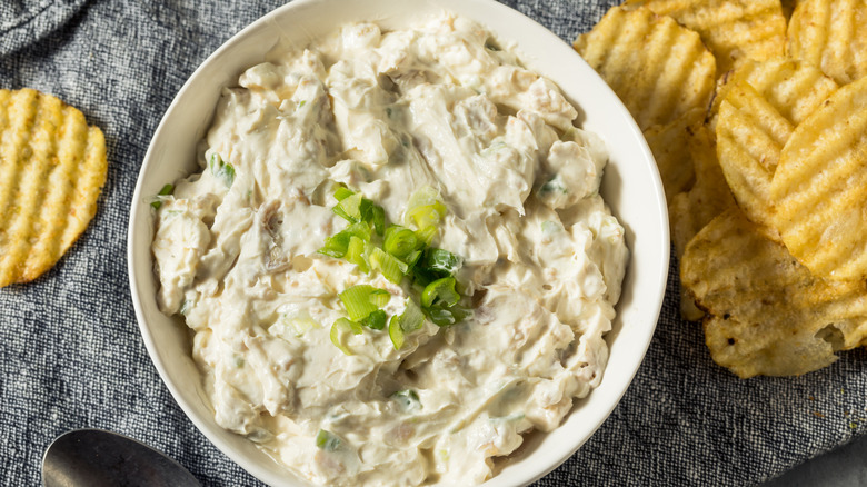 A bowl of clam dip surrounded by ripple chips