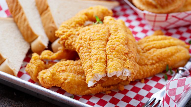 Pieces of fried catfish with bread slices on a plate