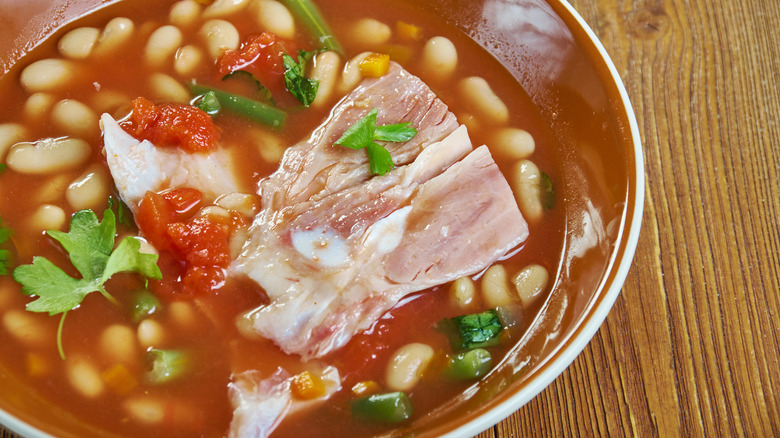 Bowl of Southern pinto beans with ham hocks on wooden table
