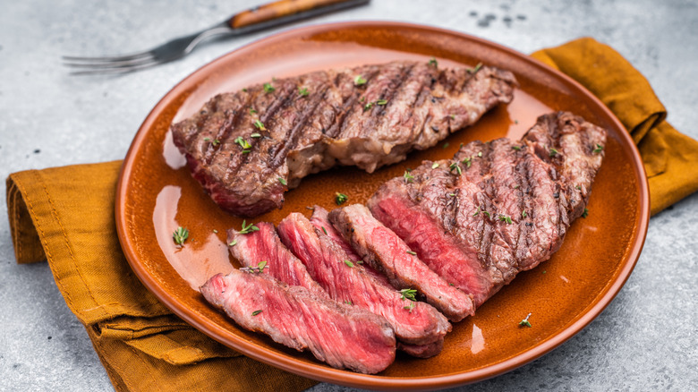 Brown plate of steak with knife