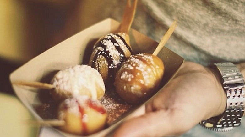 A person holding a paper plate of deep fried butter