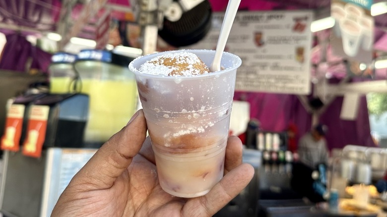 A person holding a deep-fried beverage at the State Fair of Texas