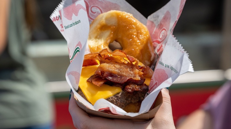 A person holding a donut burger at the Kentucky State Fair