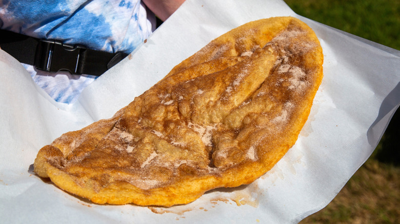 A person holding an elephant ear pastry