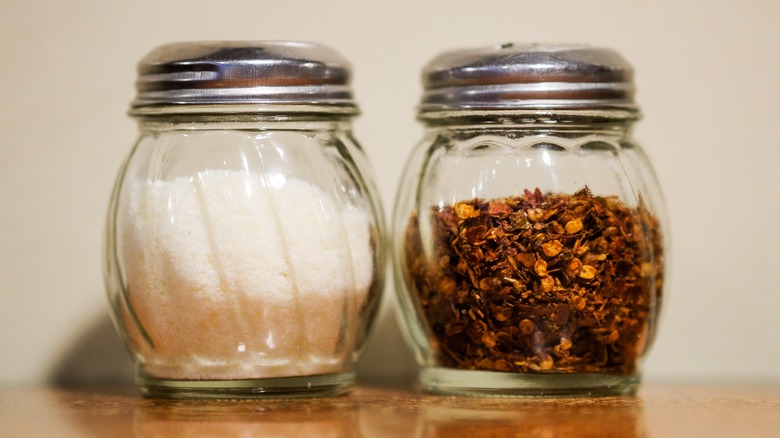 Shakers of Parmesan cheese and red chili flakes