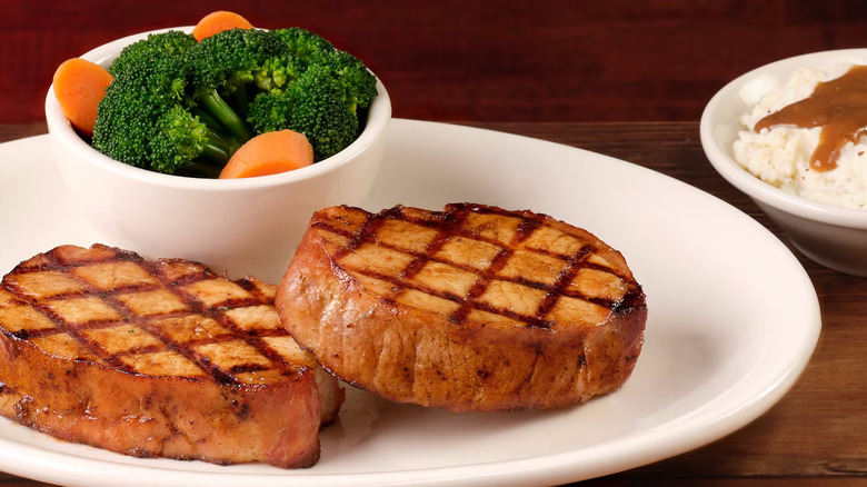 Two pork chops on a plate with vegetables at Texas Roadhouse