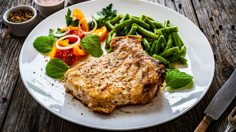 A pork chop on a plate with vegetables