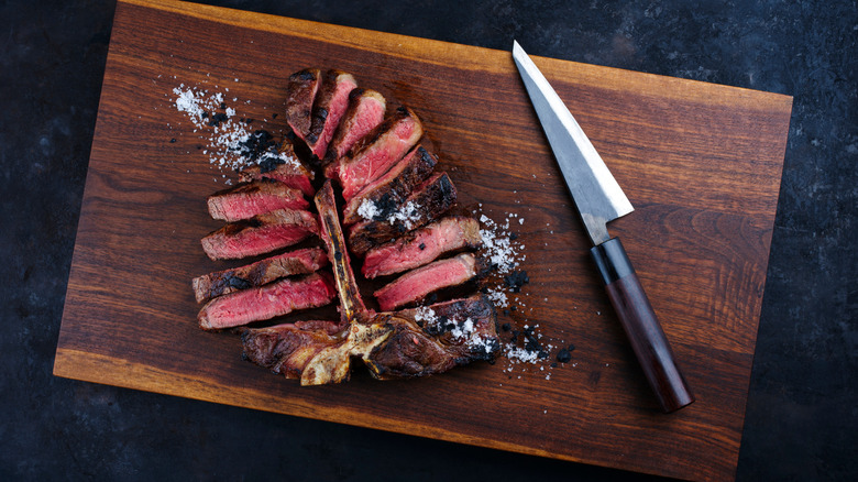 Porterhouse steak carved off the bone on a wooden cutting board