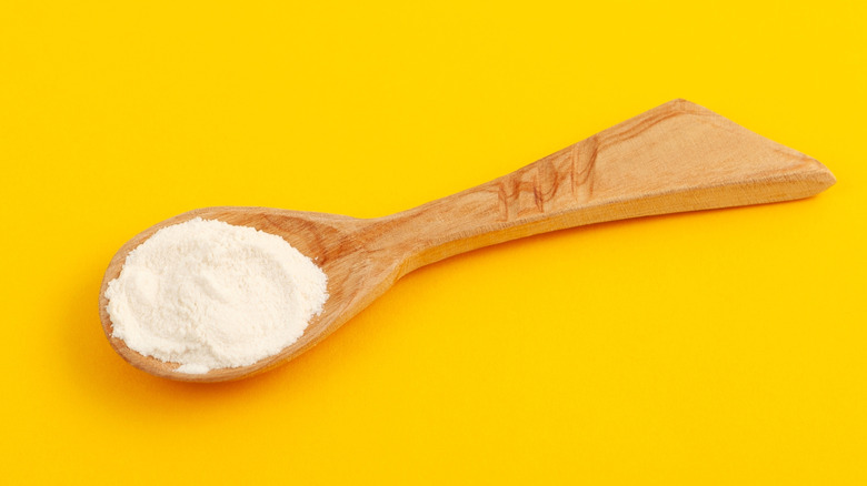 wooden spoon with xanthan gum on yellow background
