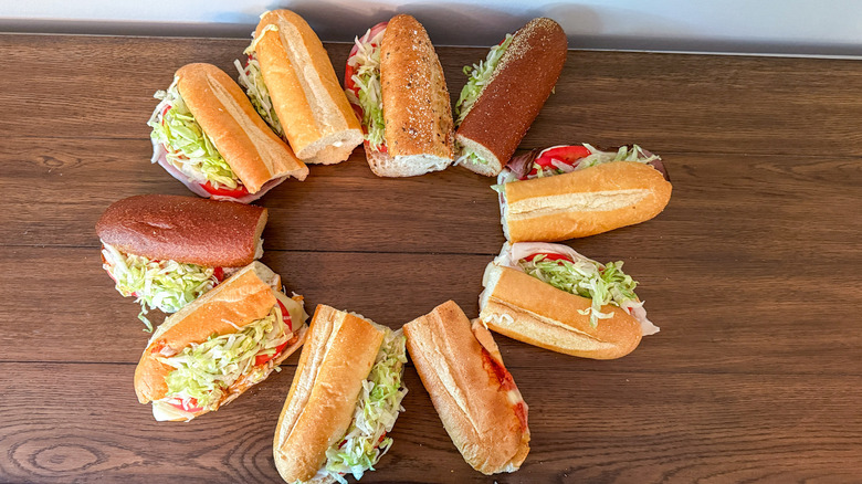 Sub sandwiches arranged in a circle on wooden table