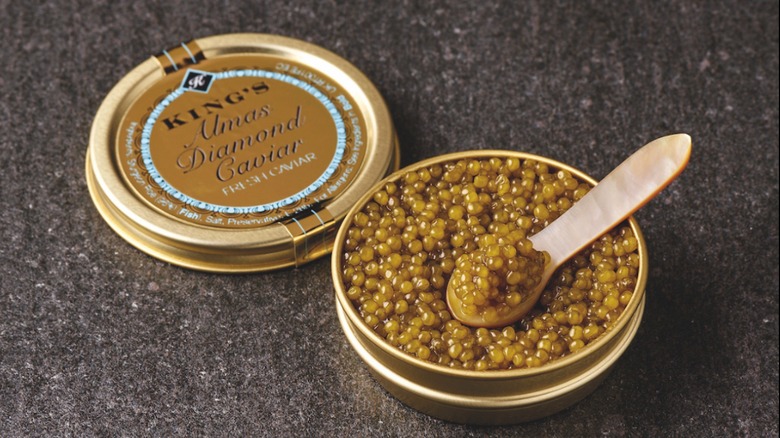 Open tin of Almas caviar with a small spoon scooped into it