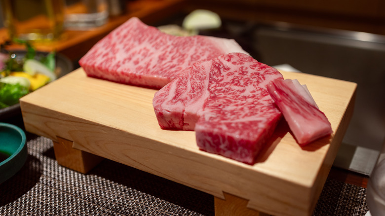 Slices of raw Kobe beef on a wooden cutting board