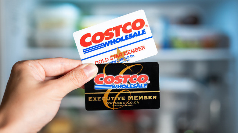 A person holding two Costco membership cards