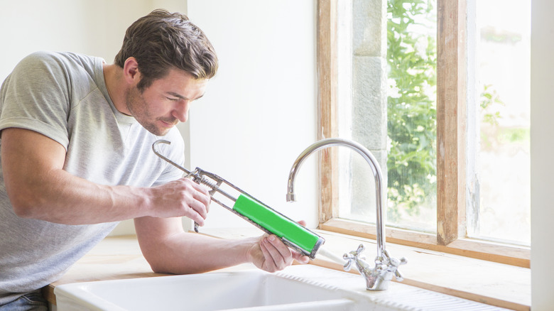 Man caulking edges around sink