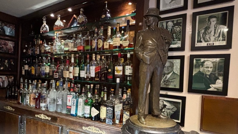 Patsy's Bar with bottles and statue of Frank Sinatra standing against 8x10s of celebrities on the wall