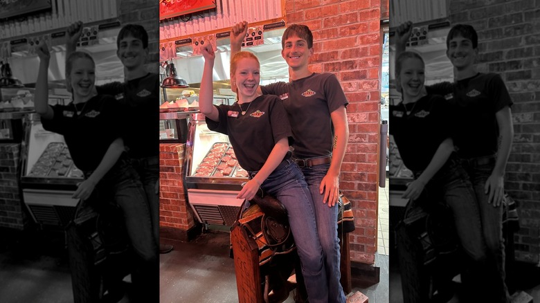 Two Texas Roadhouse employees sitting on the birthday saddle