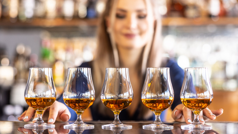 Bartender setting flight of bourbons on bar top