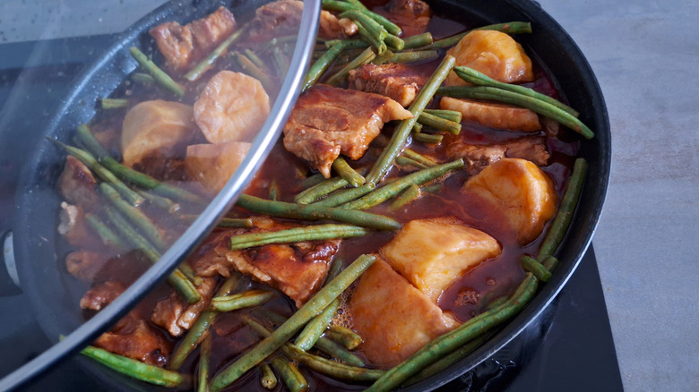 A skillet of braised pork with potatoes and green beans