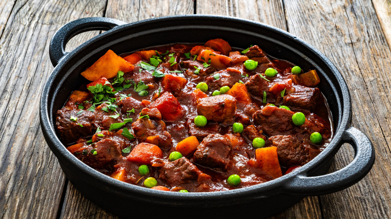 A black pot of beef stew on a wooden table