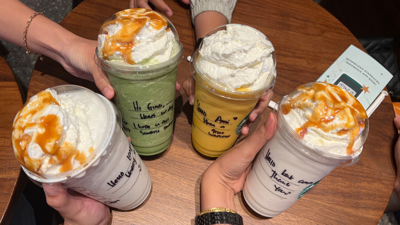 Four people hold their Starbucks Frappuccinos.