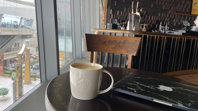 A Starbucks mug and laptop sit on a table.
