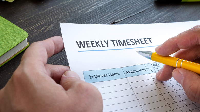 Man filling in paper timesheet