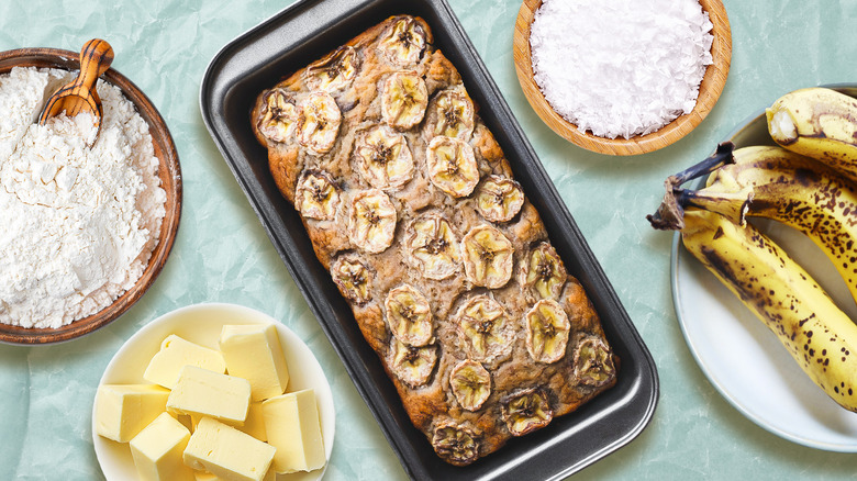 Banana bread surrounded by ingredients on blue background