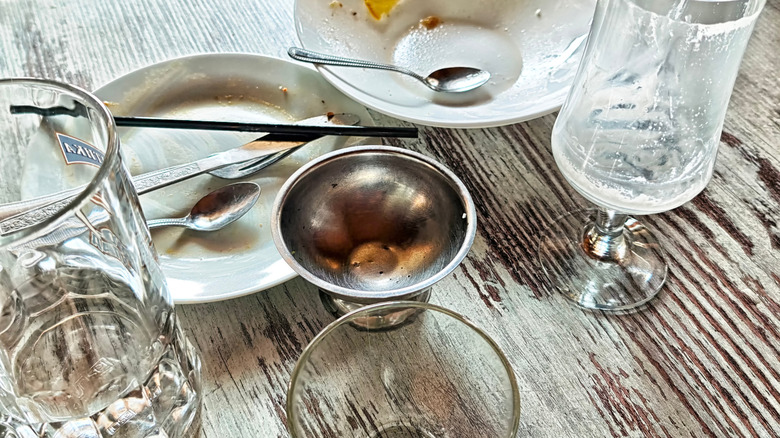 Dirty plates and empty glasses grouped together on a restaurant table