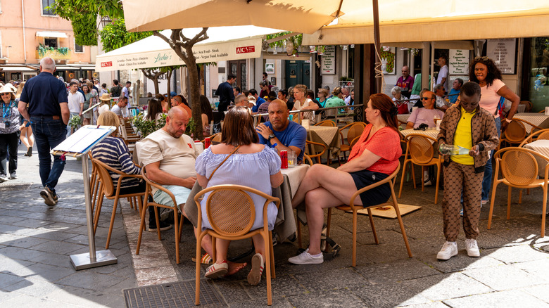 Group of people sitting at a table on a busy restaurant patio