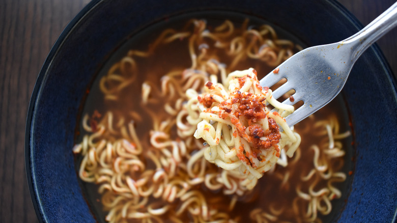 Bowl of ramen with spices on fork