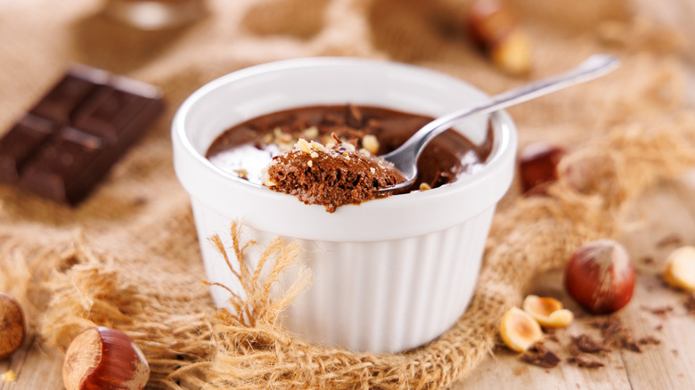 Chocolate pudding on a spoon with chopped and whole hazelnuts