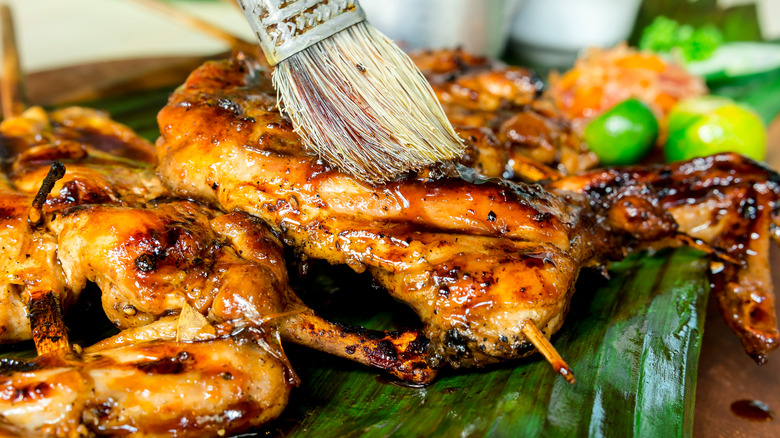Applying marinade to juicy barbecued chicken with a brush