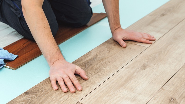 Up-close of man's hands laying laminate flooring