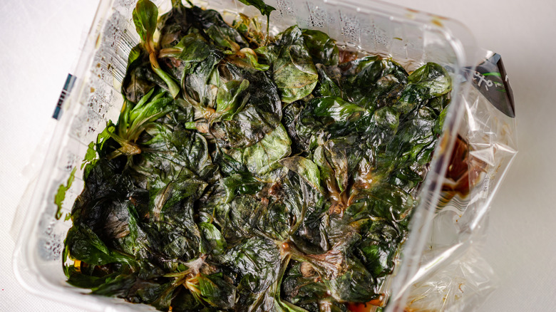 Plastic container full of old greens and soy sauce