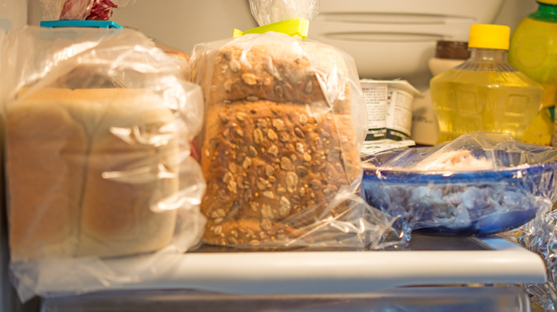Two loaves of bread in refrigerator along with leftovers and other items