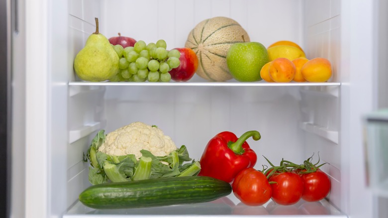 Various fruits and vegetables on two refrigerator shelves