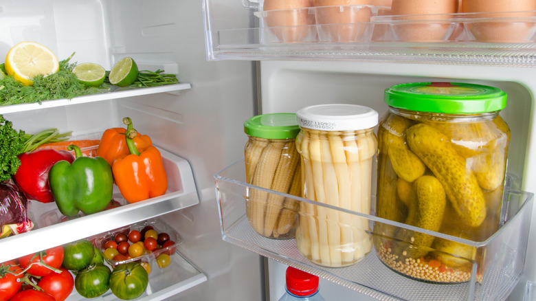 Open refrigerator showing a jar of pickles on one door shelf