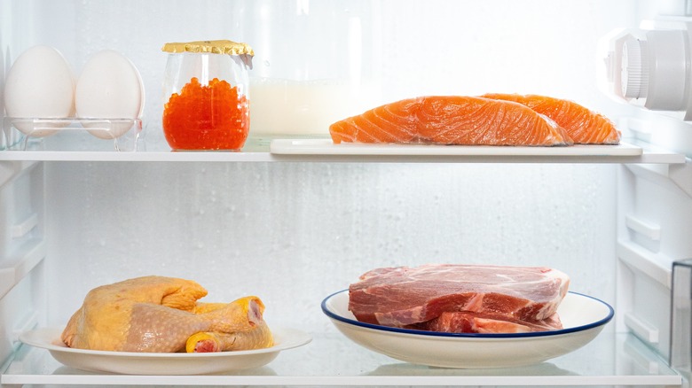 Plates of meat, fish, and chicken in fridge