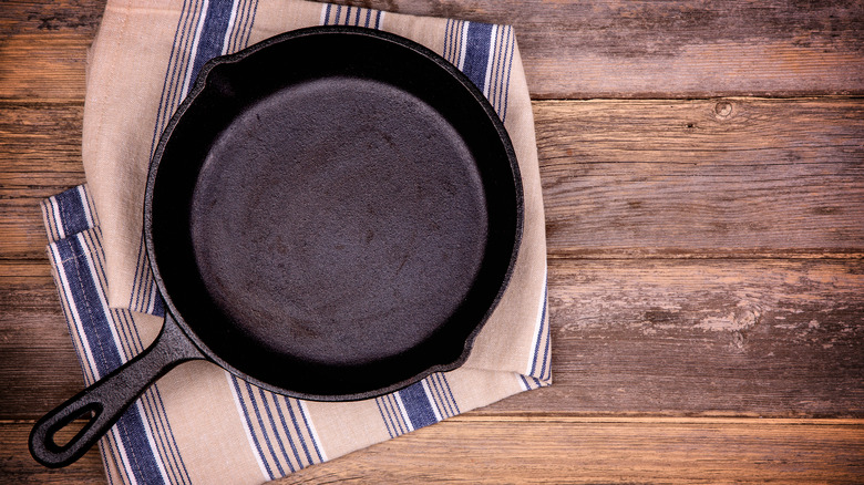 Cast iron skillet with towel and wooden surface