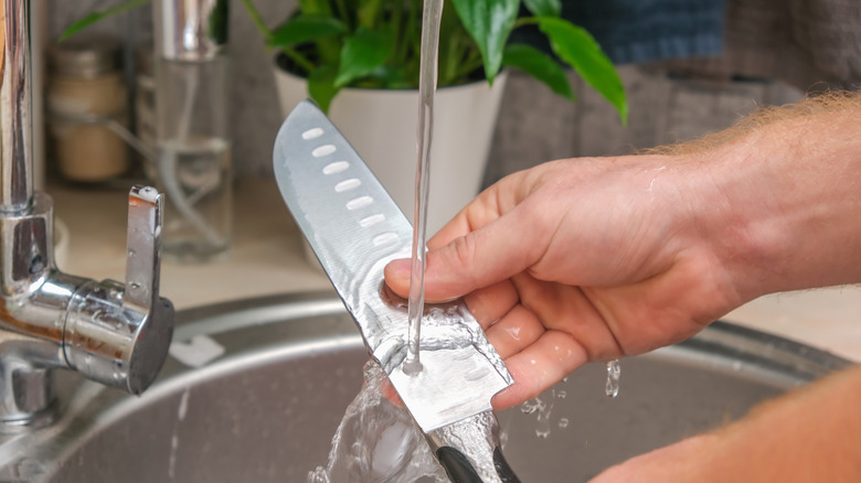 Person cleaning a knife in the sink