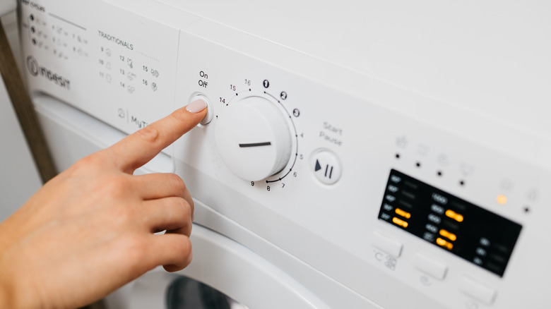 Person changing settings on washing machine