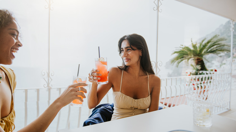 Two women drinking cocktails on an outdoor patio