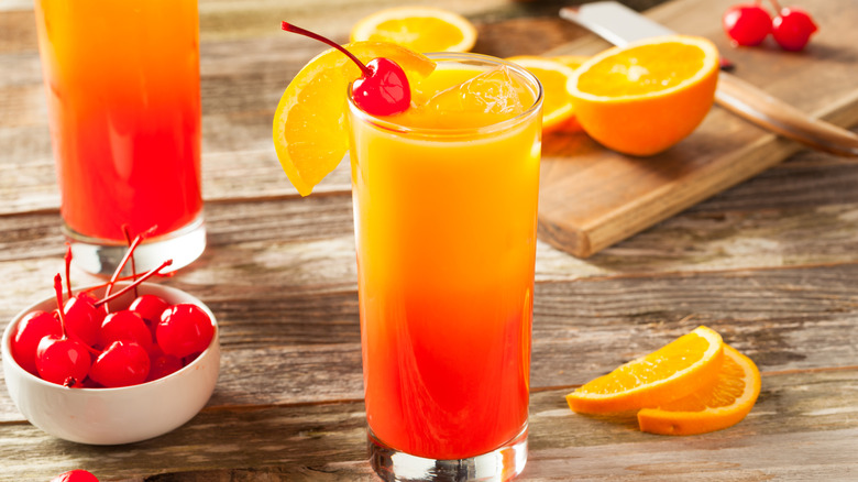 Tequila Sunrise cocktail with oranges and a bowl of cherries