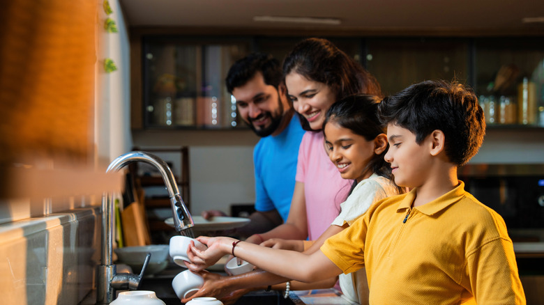 family cleaning up together in kitchen