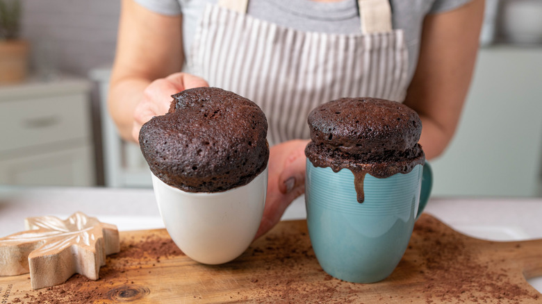 Hands placing two mug cakes on counter